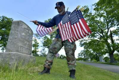 Bob Workman of Boston, a retired Marine Gunnery Sgt., and past commander of the Boston Police VFW, replaces flags at veteran's graves ahead of Memorial Day on Thursday, May 27, 2021, in the Fairview Cemetery in Boston. After more than a year of isolation, American veterans are embracing plans for a more traditional Memorial Day. After more than a year of isolation, military veterans say wreath-laying ceremonies, barbecues at local vets halls and other familiar traditions are a welcome chance for them to reconnect with fellow service members and renew solemn traditions honoring the nation's war dead. (AP Photo/Josh Reynolds)