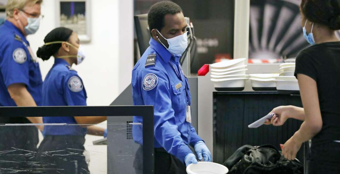FILE - In this May 18, 2020, file photo, Transportation Security Administration officers wear protective masks at a security screening area at Seattle-Tacoma International Airport in SeaTac, Wash. The Biden administration says it is moving to increase the pay and union rights for security screeners at the nation’s airports. The Department of Homeland Security directed the acting head of the TSA to come up with a plan within 90 days to raise the pay of the screeners and expand their rights to collective bargaining.  (AP Photo/Elaine Thompson, File)
