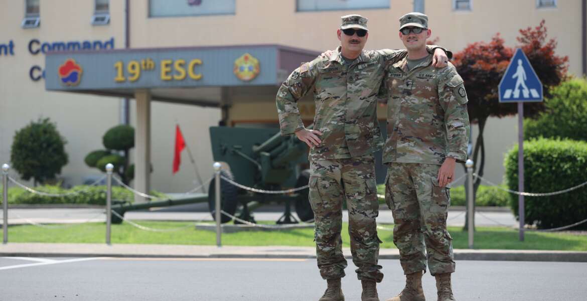 Staff Sgt. Galen Peterson, left, an ammunition NCO with Distribution Management Center, 19th Expeditionary Sustainment Command, poses with his son Spc. Justin Peterson, a Religious Affairs Specialist with 94th Military Police Battalion, in front of 19th ESC headquarters on Camp Henry. After growing up as an Army brat, Spc. Peterson enlisted in the Army in 2018 and now father and son are both stationed in Korea. (Capt. Cortland Henderson)