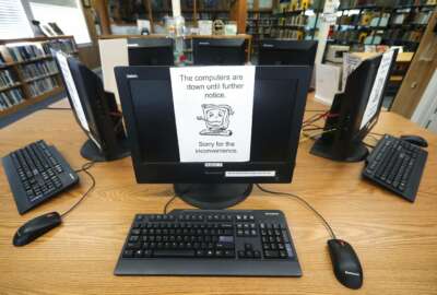 FILE - In this Aug. 22, 2019, file photo, signs on a bank of computers tell visitors that the machines are not working at the public library in Wilmer, Texas. The Associated Press has learned new details about a ransomware attack that affected roughly two dozen Texas communities two years ago. Thousands of pages obtained by AP and interviews with people involved show Texas communities struggled for days with disruptions to core government services as workers in small cities and towns endured a cascade of frustrations brought on by the sophisticated cyberattack. (AP Photo/Tony Gutierrez, File)