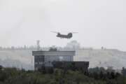 FILE - In this Sunday, Aug. 15, 2021 file photo, a U.S. Chinook helicopter flies near the U.S. Embassy in Kabul, Afghanistan, as diplomatic vehicles leave the compound amid the Taliban advance on the capital. (AP Photo/Rahmat Gul)