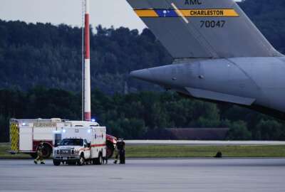 An ambulance stands next to a transport plane carrying people flown out of Afghanistan at Ramstein Air Base, in Ramstein-Miesenbach, Germany, Friday, Aug. 2021.  (Uwe Anspach/dpa via AP)