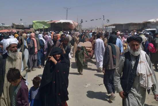 Afghan families wait for transport after entering Pakistan through a border crossing point in Chaman, Pakistan, Tuesday, Aug. 24, 2021. (AP Photo/Jafar Khan)