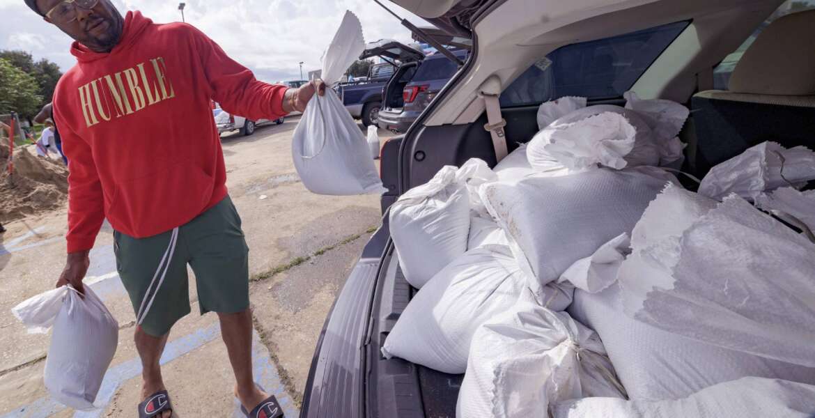 Jawan Williams loads his vehicle with sandbags before landfall of Hurricane Ida at the Frederick Sigur Civic Center in Chalmette, La., which is part of the Greater New Orleans metropolitan area, Saturday, Aug. 28, 2021.  The storm is expected to bring winds as high as 140 mph when it slams ashore late Sunday.   (AP Photo/Matthew Hinton)