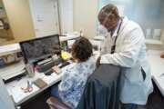 Dr. Rogers Cain, right, a primary care doctor, confers with office manager Cassandra Robinson, at his practice, Wednesday, Aug. 11, 2021, in Jacksonville, Fla. Cain said it was easier to convince his elderly patients to get the vaccine but his patients under the age of 50 remain skeptical. (AP Photo/John Raoux)