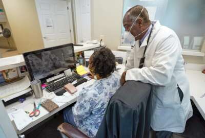 Dr. Rogers Cain, right, a primary care doctor, confers with office manager Cassandra Robinson, at his practice, Wednesday, Aug. 11, 2021, in Jacksonville, Fla. Cain said it was easier to convince his elderly patients to get the vaccine but his patients under the age of 50 remain skeptical. (AP Photo/John Raoux)