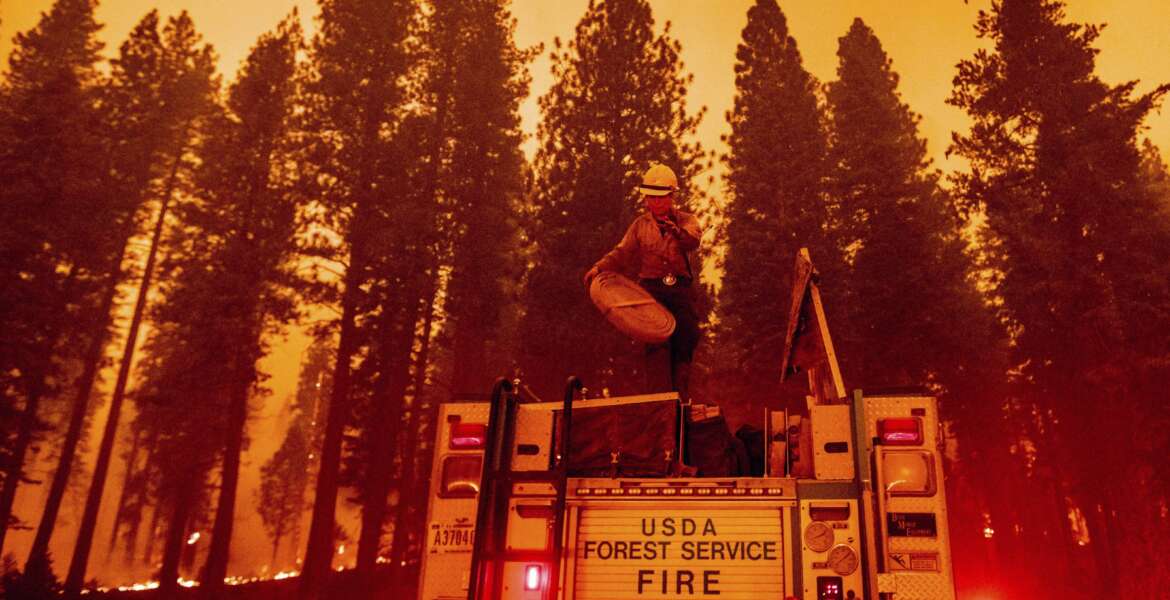 Firefighter Rosie Smith unloads hose from a truck while battling the Caldor Fire west of Strawberry in Eldorado National Forest, Calif., on Thursday, Aug. 26, 2021. (AP Photo/Noah Berger)