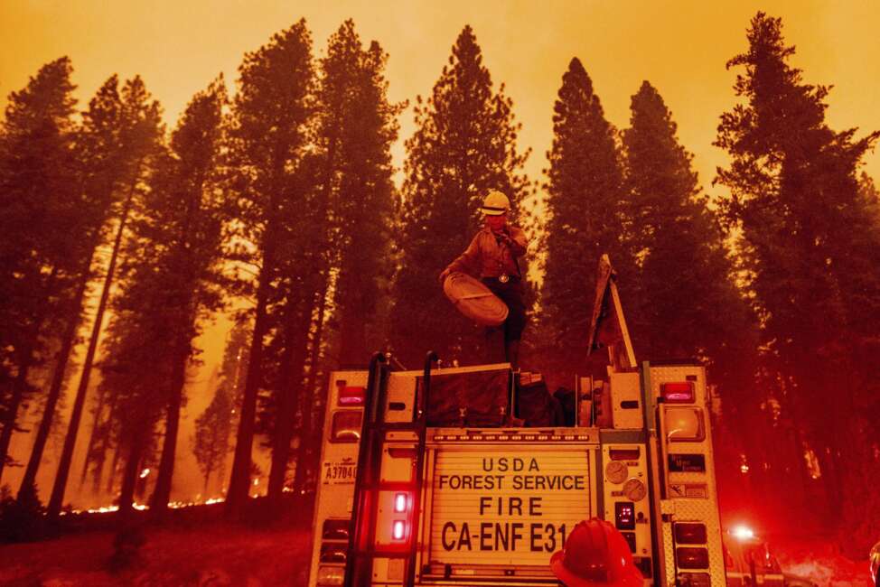 Firefighter Rosie Smith unloads hose from a truck while battling the Caldor Fire west of Strawberry in Eldorado National Forest, Calif., on Thursday, Aug. 26, 2021. (AP Photo/Noah Berger)