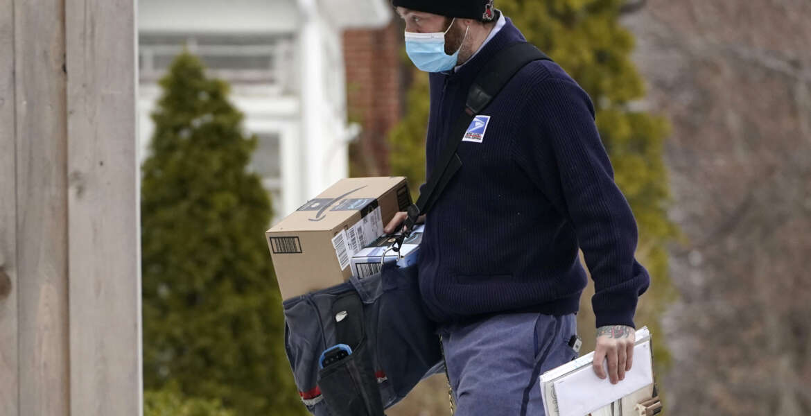 Postal carrier Josiah Morse delivers mail and packages, Wednesday, Feb. 3, 2021, in Portland, Maine. The U.S. Postal Service's stretch of challenges didn't end with the November general election and tens of millions of mail-in votes. The pandemic-depleted workforce fell further into a hole during the holiday rush, leading to long hours and a mountain of delayed mail. (AP Photo/Robert F. Bukaty)