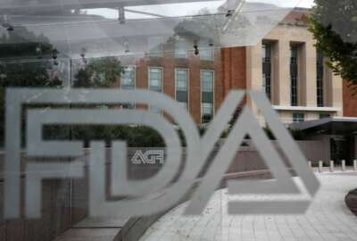 FILE - This Thursday, Aug. 2, 2018, file photo shows the U.S. Food and Drug Administration building behind FDA logos at a bus stop on the agency's campus in Silver Spring, Md. On Friday, Sept. 24, 2021, The Associated Press reported on stories circulating online incorrectly asserting that experts with the Food and Drug Administration revealed that the COVID-19 vaccines are killing at least two people for every person they save. But FDA experts did not say this, and strongly refuted this false claim in an email to The Associated Press. A speaker who is not affiliated with the FDA made these statements during the open public hearing portion of a Sept. 17 FDA vaccine advisory panel meeting. (AP Photo/Jacquelyn Martin, File)