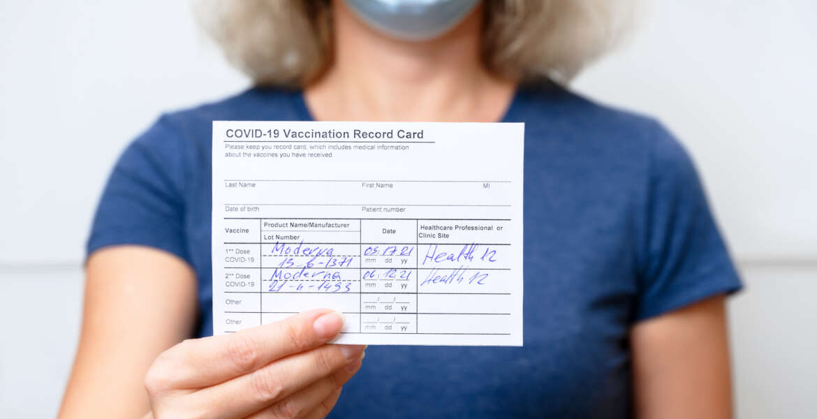 Moscow - Sep 12, 2021: Vaccinated young woman showing COVID-19 Vaccination Record Card, healthy person in mask after getting corona virus vaccine. Coronavirus vaccine shot and immunization mandate.