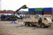 Forklift in motion at a military shipping yard at evening against setting sun.