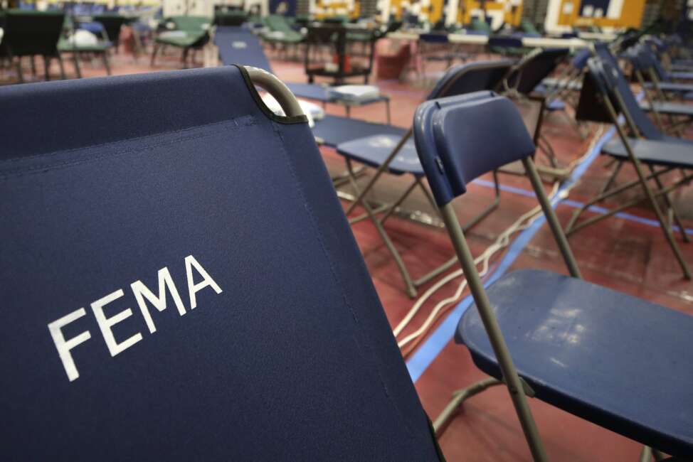 FILE - In this March 24, 2020, file photo, a portable cot with the Federal Emergency Management Agency logo FEMA printed on the backrest, along with other cots, line the basketball court at a makeshift medical facility in a gymnasium at Southern New Hampshire University in Manchester, N.H.  On Friday, Oct. 22, The Associated Press reported on stories circulating online incorrectly claiming FEMA workers aren’t subject to a vaccine mandate, and also falsely asserting that they’re being used to replace health care personnel who refuse to comply with such mandates.  (AP Photo/Charles Krupa, File)