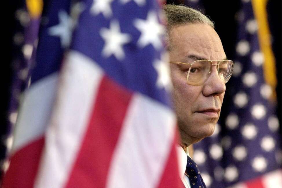 FILE  - In this Feb. 15, 2001 file photo, Secretary of State Colin Powell looks on as President Bush addresses State Department employees at the State Department in Washington. Powell, former Joint Chiefs chairman and secretary of state, has died from COVID-19 complications, his family said Monday, Oct. 18, 2021. (AP Photo/Kenneth Lambert)