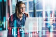 Young woman working at modern office.Technical price graph and indicator, red and green candlestick chart and stock trading computer screen background. Double exposure. Trader analyzing data