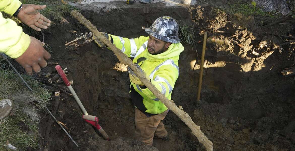 A cut lead pipe is pulled from a dig site for testing at a home in Royal Oak, Mich., on Tuesday, Nov. 16, 2021. Communities with lead pipes could see higher test results for lead in their tap water if a new method of water sampling goes into effect. The Detroit suburb of Royal Oak historically had low test results but it had to notify the public of a problem after the state mandated new sampling methods. (AP Photo/Carlos Osorio)