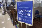 In this Saturday, Oct. 23, 2021, photograph, a sign notifies customers that COVID-19 vaccinations are available at a pharmacy in a grocery store in Monument, Colo. Millions of U.S. workers now have a Jan. 4 deadline to get a COVID vaccine. The federal government on Thursday, Nov. 4, 2021 announced new vaccine requirements for workers at companies with more than 100 employees as well as workers at health care facilities that treat Medicare and Medicaid patients. (AP Photo/David Zalubowski)