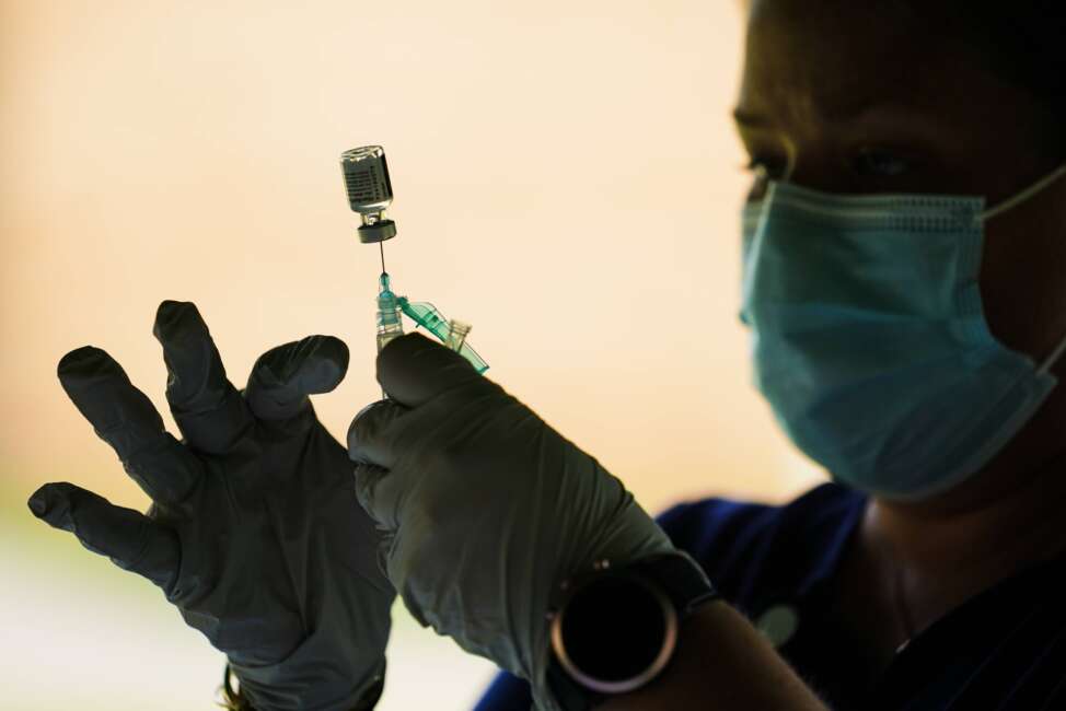 FILE - In this Sept. 14, 2021, file photo, a syringe is prepared with the Pfizer COVID-19 vaccine at a clinic at the Reading Area Community College in Reading, Pa.  Millions of U.S. workers now have a Jan. 4 deadline to get a COVID vaccine. The federal government on Thursday, Nov. 4, 2021 announced new vaccine requirements for workers at companies with more than 100 employees as well as workers at health care facilities that treat Medicare and Medicaid patients.. (AP Photo/Matt Rourke, File)