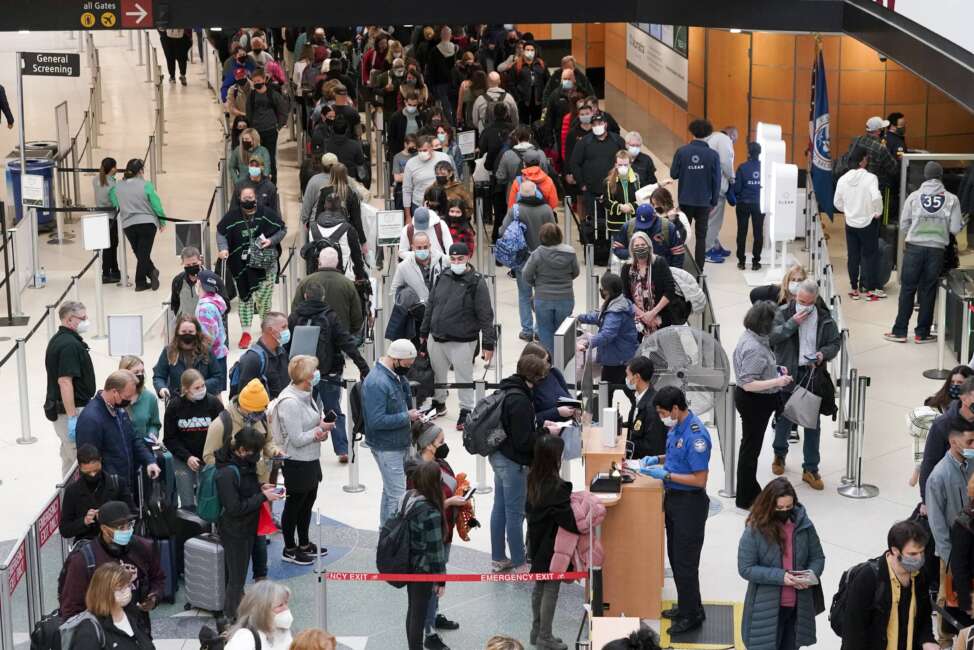 FILE - Travelers wear masks as they wait in a line for a TSA security check, Dec. 10, 2021, at Seattle-Tacoma International Airport in Seattle. President Joe Biden on Monday, Dec. 13, 2021, will sign an executive order aimed at saving Americans time and frustration when seeking a broad array of federal services, like renewing passports, applying for Social Security benefits and getting aid after natural disasters. (AP Photo/Ted S. Warren, File)