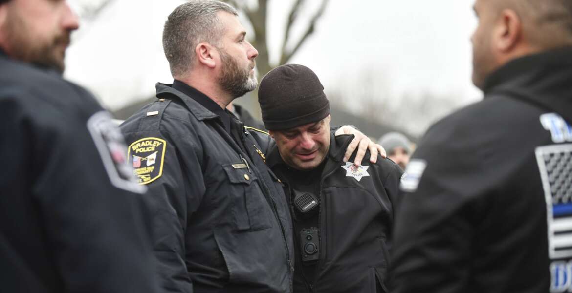 Bradey Police Lt. Philip Trudeau, left, comforts Bourbonnais Police officer Andy Cox following a ceremonial procession for fallen Bradley Police Sgt. Marlene Rittmanic, Thursday, Dec. 30, 2021,  in Bourbonnais, Ill. Rittmanic died after a shooting at a Comfort Inn the night before. (Tiffany Blanchette/The Daily Journal via AP)