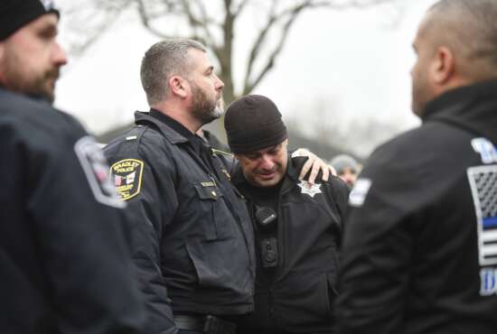 Bradey Police Lt. Philip Trudeau, left, comforts Bourbonnais Police officer Andy Cox following a ceremonial procession for fallen Bradley Police Sgt. Marlene Rittmanic, Thursday, Dec. 30, 2021,  in Bourbonnais, Ill. Rittmanic died after a shooting at a Comfort Inn the night before. (Tiffany Blanchette/The Daily Journal via AP)