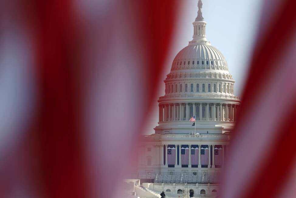 FILE - The U.S. Capitol is seen through a display of flags on the National Mall, one day after the inauguration of President Joe Biden, on Jan. 21, 2021, in Washington. Just over a year ago, millions of energized young people, women, voters of color and independents joined forces to send Joe Biden to the White House. But 12 months after he entered the Oval Office, many describe a coalition in crisis. (AP Photo/Rebecca Blackwell, File)