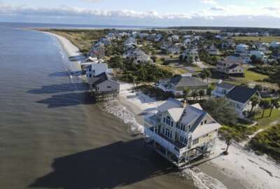 FILE - Water laps the bottom level of four homes in Harbor Island, S.C., Saturday, Oct. 30, 2021, which had to be abandoned after years of beach erosion and damage from Hurricane Matthew in 2016. Facing state budgets that are flush with cash, Democratic and Republican governors alike want to spend part of their windfalls on projects aimed at slowing climate change and guarding against its consequences, from floods and fires to cleaning up dirty air. (AP Photo/Rebecca Blackwell, File)