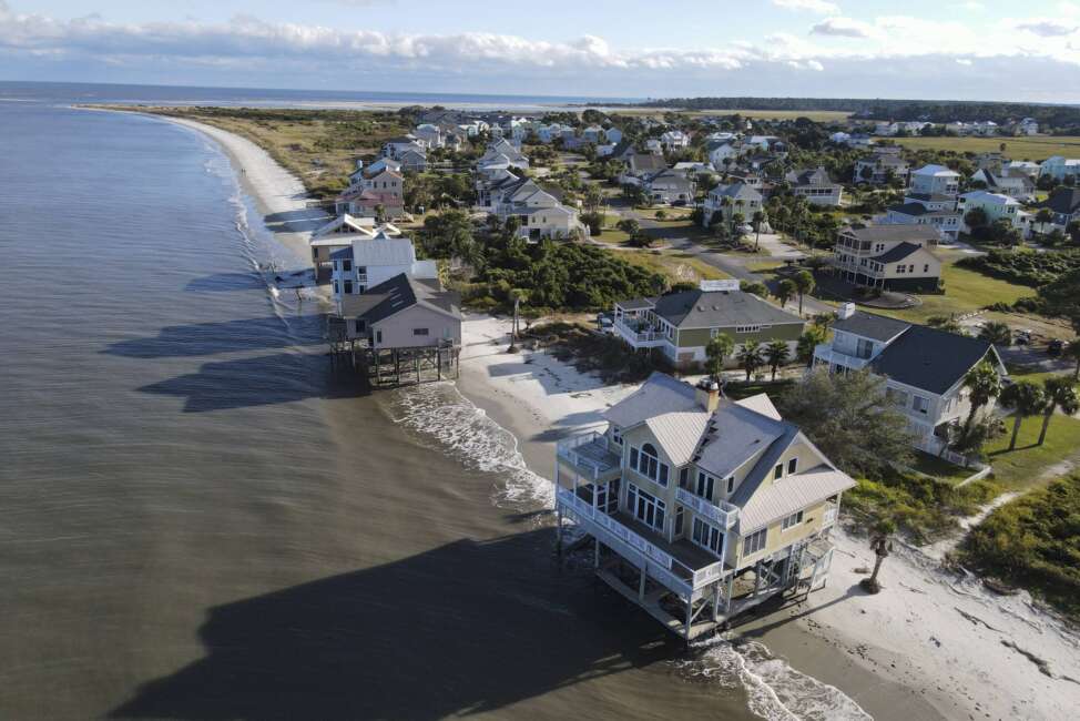 FILE - Water laps the bottom level of four homes in Harbor Island, S.C., Saturday, Oct. 30, 2021, which had to be abandoned after years of beach erosion and damage from Hurricane Matthew in 2016. Facing state budgets that are flush with cash, Democratic and Republican governors alike want to spend part of their windfalls on projects aimed at slowing climate change and guarding against its consequences, from floods and fires to cleaning up dirty air. (AP Photo/Rebecca Blackwell, File)