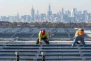 FILE - Framed by the Manhattan skyline electricians with IBEW Local 3 install solar panels on top of the Terminal B garage at LaGuardia Airport, Tuesday, Nov. 9, 2021, in the Queens borough of New York.  As climate change pushes states in the U.S. to dramatically cut their use of fossil fuels, many are coming to the conclusion that solar, wind and other renewable power sources won't be enough to keep the lights on. Nuclear power is emerging as an answer to fill the gap as states transition away from coal, oil and natural gas to reduce greenhouse gas emissions and stave off the worst effects of a warming planet. (AP Photo/Mary Altaffer, File)