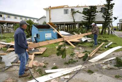 FILE - Mark Andollina, left, and Shane Holder, remove part of a roof damaged by Hurricane Zeta from the road at the Cajun Tide Beach Resort in Grand Isle, La., Oct. 30, 2020. The Department of Housing and Urban Development has laid out new guidelines for the disbursal of $2 billion in disaster-relief bloc grants, with an emphasis on climate-change mitigation and equity for underserved communities. The new guidelines spell out priorities for the use of the funds by state and local agencies that receive the Community Development Block Grants. The funds were allocated last year to aid in relief efforts for disasters that took place in 2020 in 10 states and territories.  (AP Photo/Matthew Hinton, File)