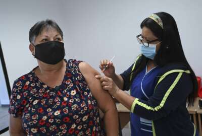 A woman receives a booster jab of COVID-19 Pfizer vaccine during a vaccination campaign in San Jose, Costa Rica, Tuesday, Jan. 18, 2022. (AP Photo/Carlos Gonzalez)