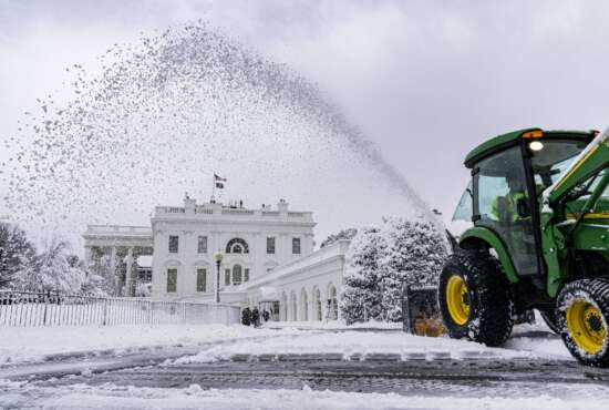 A groundskeeper clears the driveway in front of the West Wing of the White House in Washington, Monday, Jan. 3, 2022, as a winter storm blows into the Mid-Atlantic area. (AP Photo/Andrew Harnik)