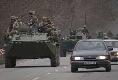Ukrainian servicemen sit atop armored personnel carriers driving on a road in the Donetsk region, eastern Ukraine, Thursday, Feb. 24, 2022. Russian President Vladimir Putin on Thursday announced a military operation in Ukraine and warned other countries that any attempt to interfere with the Russian action would lead to 