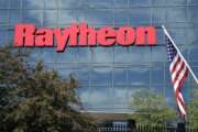 FILE - An American flag flies in front of the facade of Raytheon's Integrated Defense Systems facility, in Woburn, Mass on June 10, 2019. China said Monday, Feb. 21, 2022, it will impose new sanctions on U.S. defense contractors Raytheon Technologies and Lockheed Martin due to their arms sales to Taiwan, stepping up a feud with Washington over security and Beijing’s strategic ambitions. (AP Photo/Elise Amendola, File)