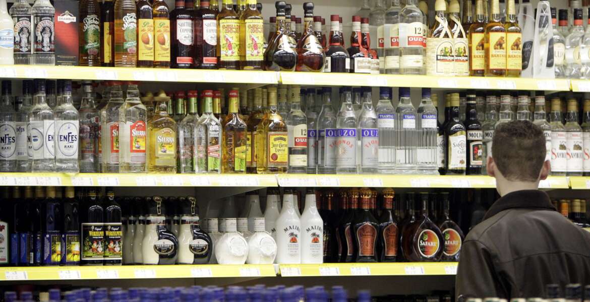 FILE - A young man stands in front of a shelve with hard liquor at a beverage market in Gelsenkirchen, western Germany, June 15, 2007. The German government's drugs czar has proposed raising the age when people can buy beer and win from 16 to 18, and cracking down on alcohol and tobacco advertising. (AP Photo/Martin Meissner, File)