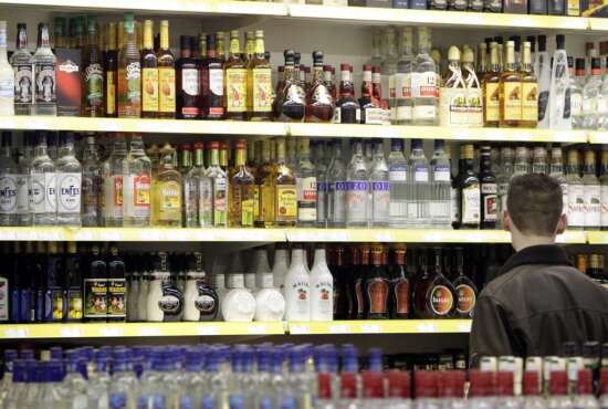 FILE - A young man stands in front of a shelve with hard liquor at a beverage market in Gelsenkirchen, western Germany, June 15, 2007. The German government's drugs czar has proposed raising the age when people can buy beer and win from 16 to 18, and cracking down on alcohol and tobacco advertising. (AP Photo/Martin Meissner, File)