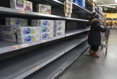 FILE - A woman looks over shelves, some of which are empty, at a Walmart store in Teterboro, N.J., on Jan. 12, 2022. The Justice Department is launching a new initiative aimed at identifying companies that exploit supply chain disruptions in the U.S. to make increased profits in violation of federal antitrust laws. (AP Photo/Seth Wenig, File)