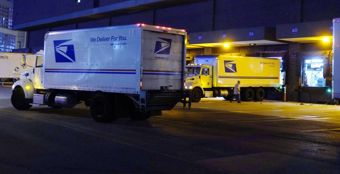 FILE - Delivery trucks arrive at the loading dock at the United States Postal Service sorting and processing facility Nov. 18, 2021, in Boston. The Environmental Protection Agency is raising concerns about a U.S. Postal Service plan to replace its huge fleet of mail-delivery trucks, saying the effort does not include enough electric vehicles. (AP Photo/Charles Krupa, File)