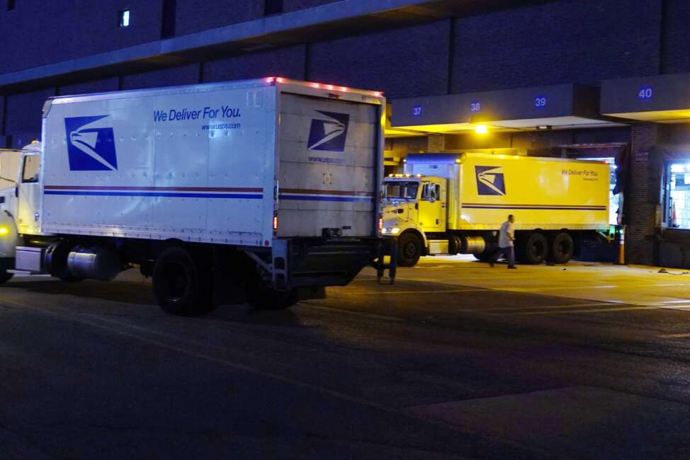 FILE - Delivery trucks arrive at the loading dock at the United States Postal Service sorting and processing facility Nov. 18, 2021, in Boston. The Environmental Protection Agency is raising concerns about a U.S. Postal Service plan to replace its huge fleet of mail-delivery trucks, saying the effort does not include enough electric vehicles. (AP Photo/Charles Krupa, File)