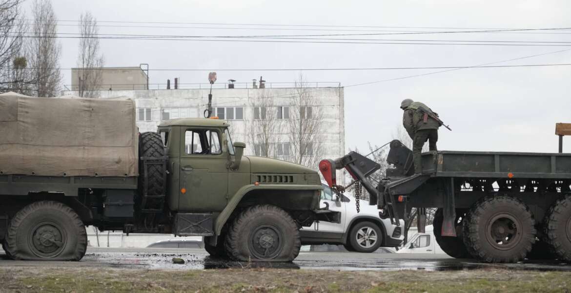 Ukrainian Army soldiers prepare to tow a damaged military truck in Kyiv, Ukraine, Friday, Feb. 25, 2022. Russia is pressing its invasion of Ukraine to the outskirts of the capital after unleashing airstrikes on cities and military bases and sending in troops and tanks from three sides. (AP Photo/Efrem Lukatsky)