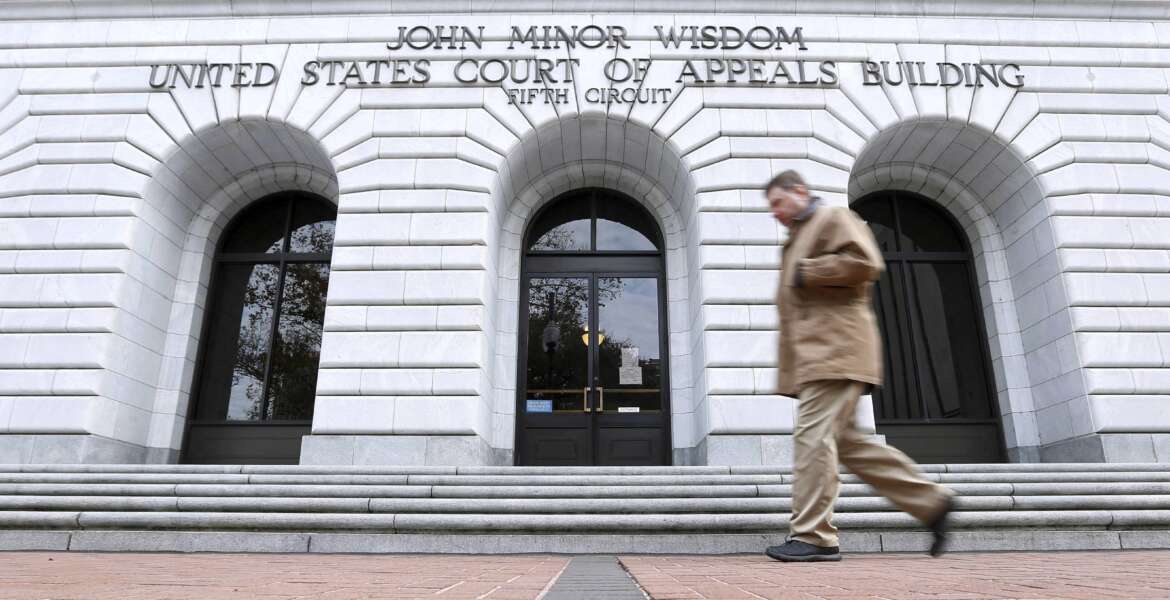 FILE - A man walks in front of the 5th U.S. Circuit Court of Appeals, Jan. 7, 2015, in New Orleans. A U.S. appeals court has declined for now to allow President Joe Biden's administration to require COVID-19 vaccinations for federal employees. The 5th U.S. Circuit Court of Appeals in New Orleans ruled 2-1 Wednesday, Feb. 9, 2022 to maintain a block on the mandate that a Texas-based federal judge issued on Jan. 21. (AP Photo/Jonathan Bachman, file)