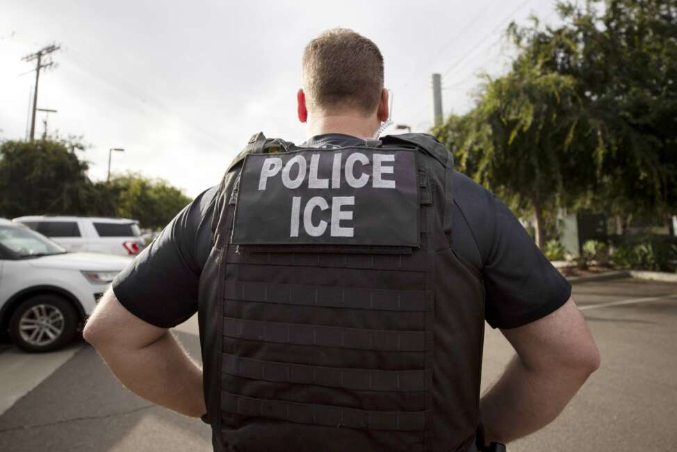 FILE - A U.S. Immigration and Customs Enforcement (ICE) officer looks on during an operation in Escondido, Calif.,  July 8, 2019.  Immigration enforcement arrests in the interior of the U.S. fell over the past year as the Biden administration shifted its enforcement focus to people in the country without legal status who have committed serious crimes.  (AP Photo/Gregory Bull, File)