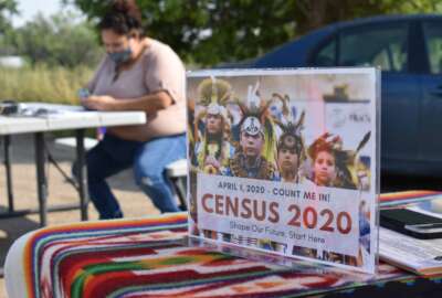 FILE - In this Aug. 26, 2020 photo, a sign promoting Native American participation in the U.S. census is displayed as Selena Rides Horse enters information into her phone on behalf of a member of the Crow Indian Tribe in Lodge Grass, Mont. The U.S. Census Bureau will release reports Thursday, March 9, 2022 that show how good of a job the agency believes it did in counting every U.S. resident during the 2020 census. Native American tribes and advocates launched well-financed campaigns to ensure a more accurate count.(AP Photo/Matthew Brown, File)