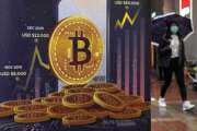 FILE - An advertisement for Bitcoin cryptocurrency is displayed on a street in Hong Kong, Thursday, Feb. 17, 2022. Bitcoin prices have surged in recent days, Wednesday, March 2,  as investors once again appear to view the volatile cryptocurrency as safe haven for their money in the midst of rising geopolitical tensions. (AP Photo/Kin Cheung, File)