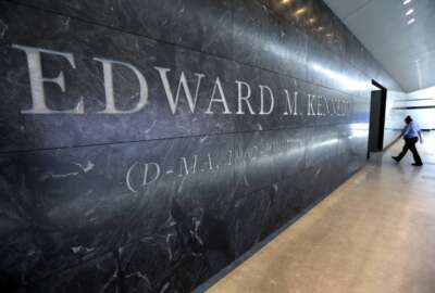 A passer-by walks near the engraved name of the late U.S. Sen. Edward M. Kennedy near the main entrance to the Edward M. Kennedy Institute, in Boston, March 23, 2015. An Associated Press review finds state and local governments have spent nearly $1 billion worth of federal coronavirus aid on projects that have little to do with combating the pandemic. Lawmakers delivered $5 million to pay off debts of the Edward M. Kennedy Institute for the U.S. Senate, a nonprofit established to honor the senator that has struggled financially.  (AP Photo/Steven Senne, File)