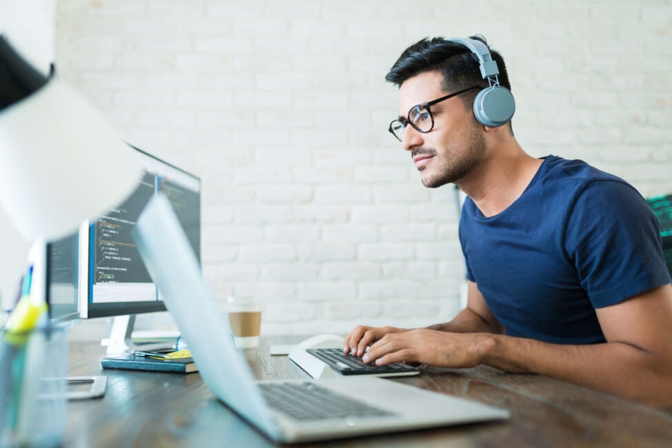 Handsome young male software developer programming codes while working from home