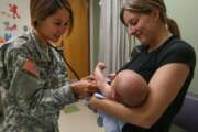 Army doctor examines baby held by its mother