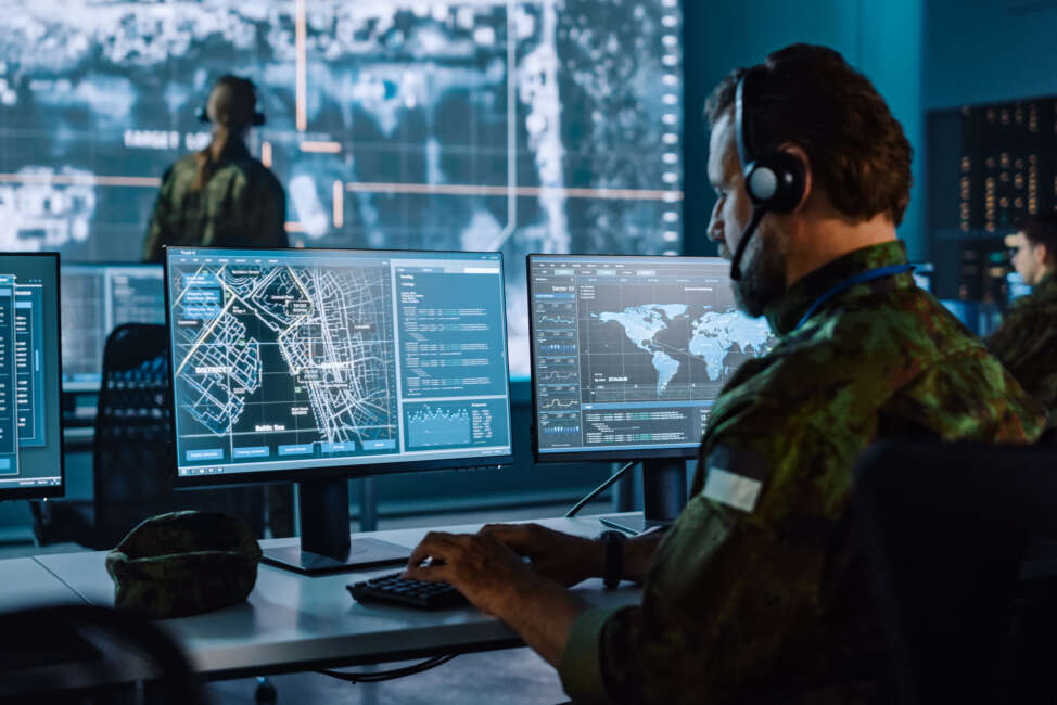 Military Surveillance Officer Working on a City Tracking Operation in a Central Office Hub for Cyber Control and Monitoring for Managing National Security, Technology and Army Communications.