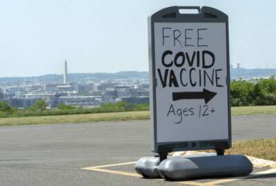 FILE - Overlooking downtown Washington and the Washington Monument, a sign advertises a free vaccine drive with Pfizer COVID-19 vaccinations for members of the community 12 years and up, May 19, 2021, at a clinic held by Community of Hope, in Washington. The U.S. came the closest to health care for all for the first time during the coronavirus pandemic. It was for just one condition, COVID 19. Now, things are reverting to the way they were as federal money for the uninsured dries up. Lack of an insurance card could become a barrier to timely care for COVID. (AP Photo/Jacquelyn Martin, File)