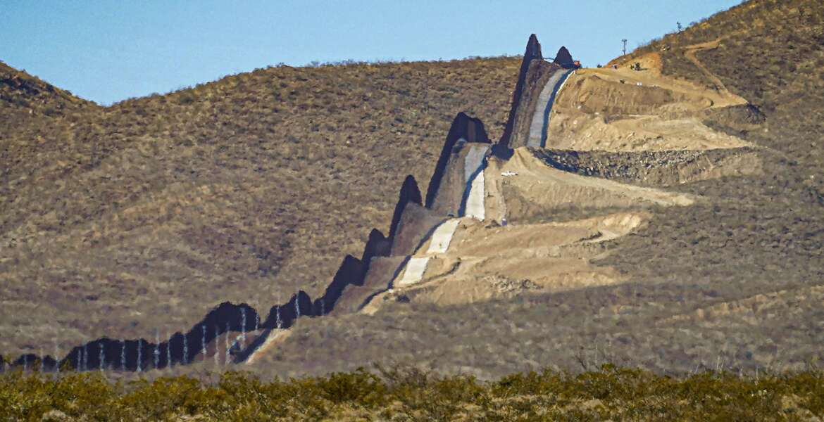 FILE - A U.S. government-built section of border wall snakes through the Sonoran Desert just west of the San Bernardino National Wildlife Refuge, separating Mexico, left, and the United States, Dec. 9, 2020, in Douglas, Ariz. A prosecutor told jurors in closing arguments at a criminal trial, Tuesday, May 31, 2022, that there is overwhelming evidence that organizers of a 